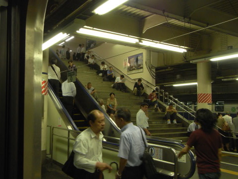 台風接近で電車の止まった上野駅の階段に座り込む人々